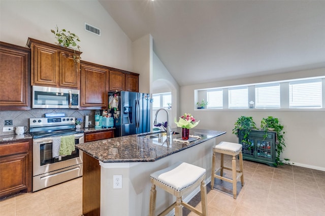 4806 Ashbury Ln, Mansfield, TX 76063 - kitchen featuring stainless steel appliances, a sink, a kitchen breakfast bar, dark stone countertops, and decorative backsplash