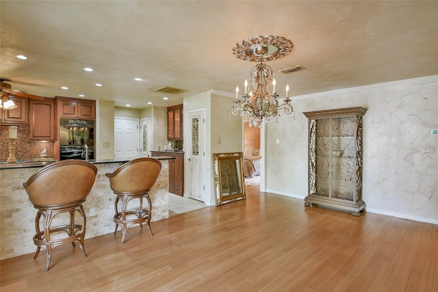 4009 Scenic Way, Granbury, TX 76049 - kitchen with a chandelier, oven, brown cabinets, light wood finished floors, and glass insert cabinets
