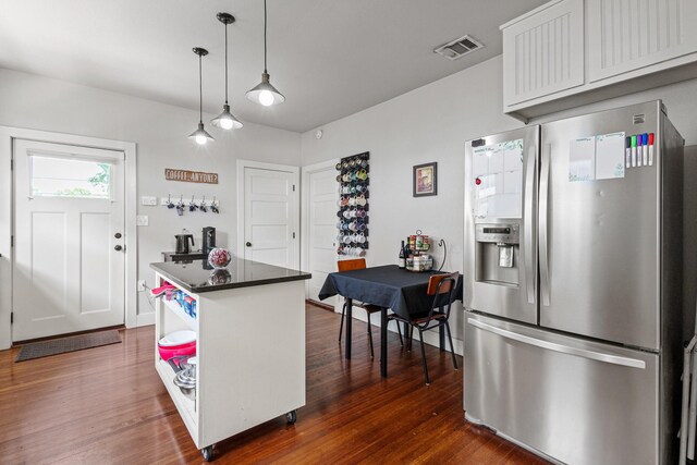 2236 Alston Ave, Fort Worth, TX 76110 - kitchen featuring stainless steel fridge with ice dispenser, dark wood finished floors, dark countertops, hanging light fixtures, and a center island