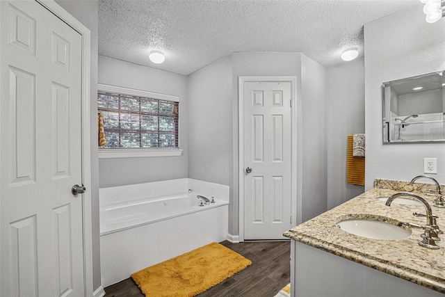 7333 Mesa Verde Trl, Fort Worth, TX 76137 - bathroom featuring a garden tub, double vanity, a textured ceiling, and wood finished floors