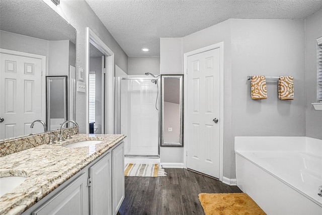 7333 Mesa Verde Trl, Fort Worth, TX 76137 - bathroom featuring a shower stall, a garden tub, double vanity, wood finished floors, and a textured ceiling