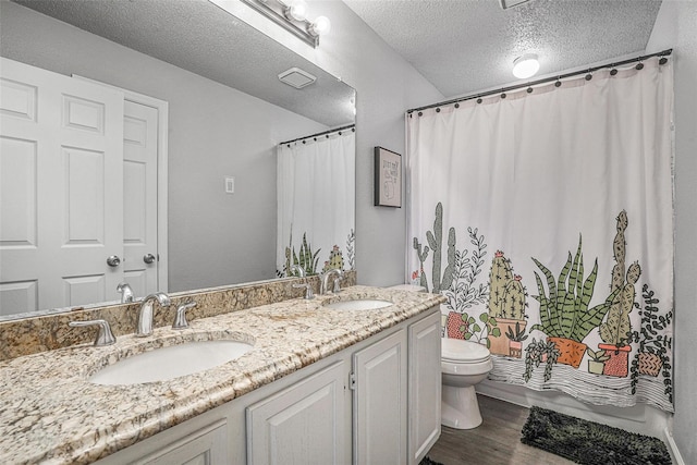 7333 Mesa Verde Trl, Fort Worth, TX 76137 - full bathroom featuring toilet, double vanity, wood finished floors, a textured ceiling, and a shower with curtain