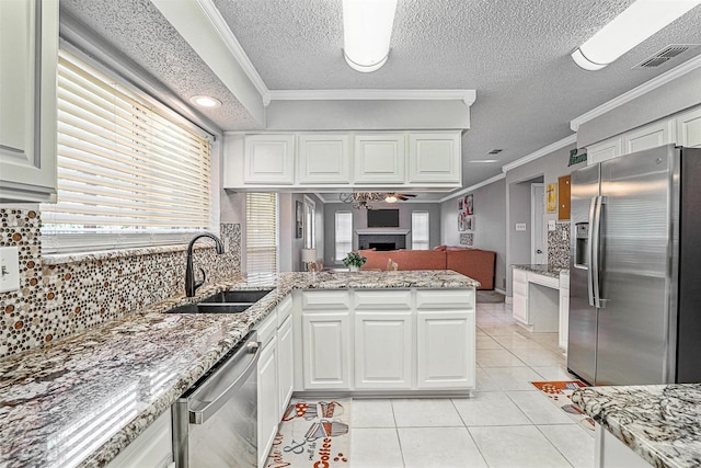 7333 Mesa Verde Trl, Fort Worth, TX 76137 - kitchen featuring stainless steel appliances, a sink, a peninsula, a fireplace, and light tile patterned flooring
