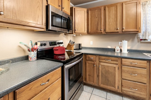 107 Camino Robles St, Gun Barrel City, TX 75156 - kitchen with stainless steel appliances, dark countertops, light tile patterned flooring, and brown cabinetry