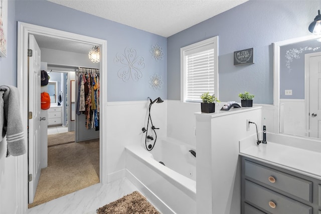 203 Marianne, Sulphur Springs, TX 75482 - bathroom with a textured ceiling, wainscoting, a bath, a walk in closet, and vanity