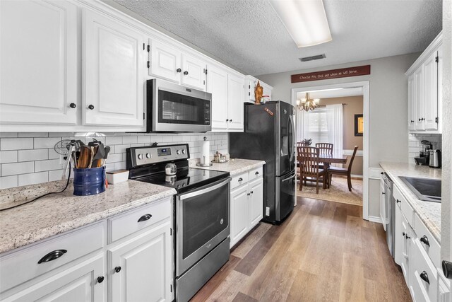 203 Marianne, Sulphur Springs, TX 75482 - kitchen with stainless steel appliances, a chandelier, white cabinetry, and a textured ceiling
