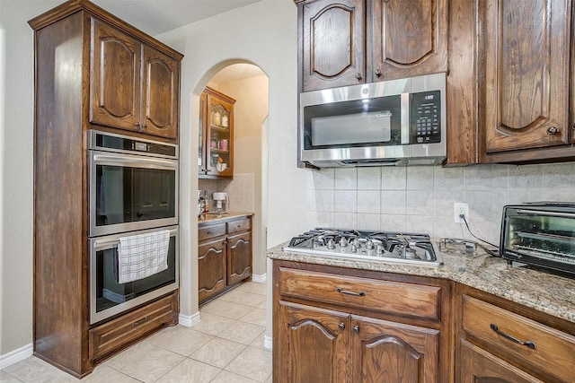 5040 Pallas Ct, Fort Worth, TX 76123 - kitchen with stainless steel appliances, tasteful backsplash, arched walkways, light tile patterned flooring, and baseboards