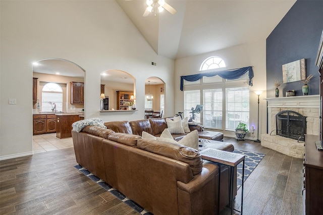 5040 Pallas Ct, Fort Worth, TX 76123 - living room with arched walkways, a ceiling fan, a stone fireplace, wood finished floors, and high vaulted ceiling