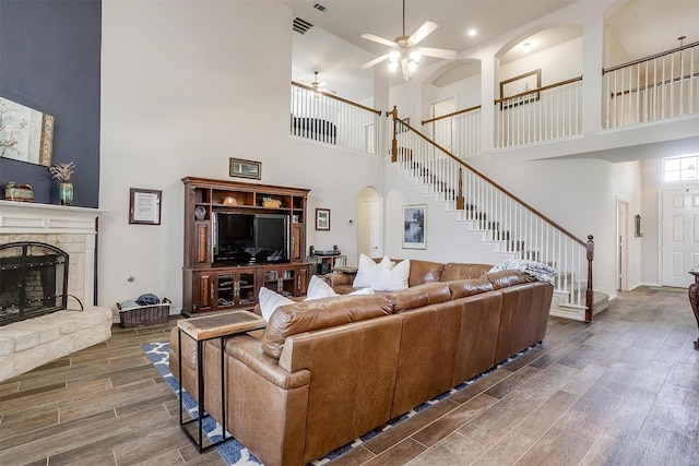 5040 Pallas Ct, Fort Worth, TX 76123 - living room featuring a towering ceiling, wood finished floors, stairs, a ceiling fan, and a fireplace
