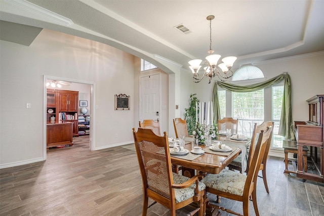 5040 Pallas Ct, Fort Worth, TX 76123 - dining space featuring a tray ceiling, a chandelier, light wood-type flooring, arched walkways, and ornamental molding