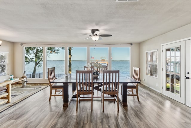 142 Peninsula Point Ter, Mabank, TX 75156 - dining area featuring wood finished floors, a water view, a ceiling fan, and a textured ceiling