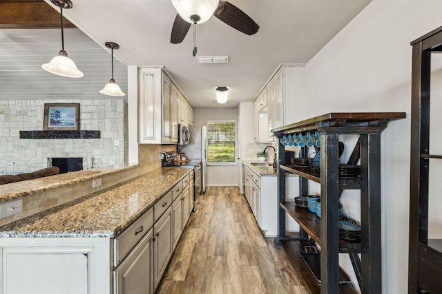 142 Peninsula Point Ter, Mabank, TX 75156 - kitchen featuring stainless steel appliances, a sink, light wood-type flooring, a ceiling fan, and light stone counters