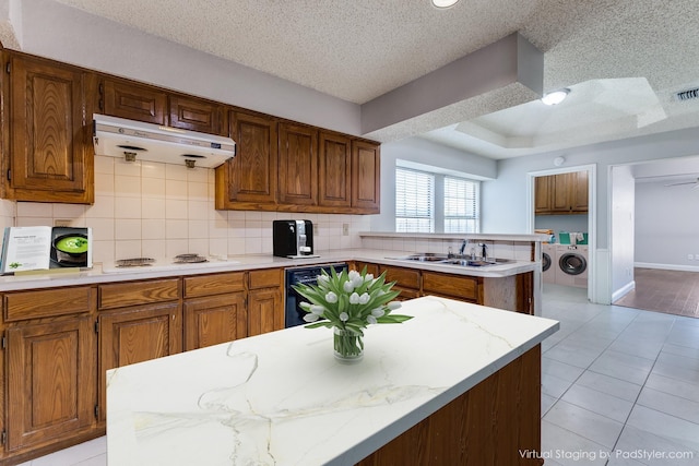 18609 Crownover Ct, Dallas, TX 75252 - kitchen featuring a sink, washer and clothes dryer, a peninsula, white cooktop, and a textured ceiling