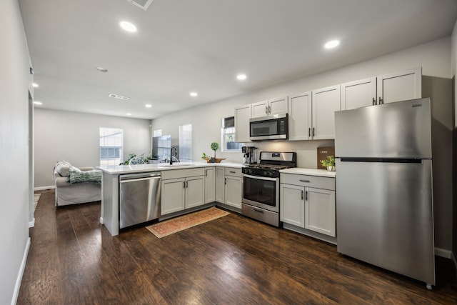1215 Morrell Ave, Dallas, TX 75203 - kitchen with appliances with stainless steel finishes, a sink, a peninsula, light countertops, and dark wood-style floors