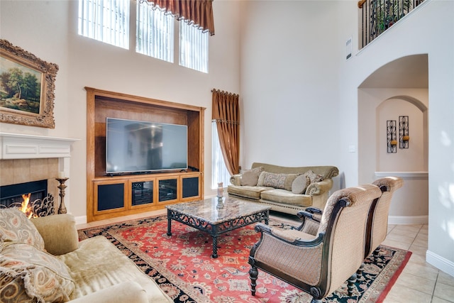 1113 Waterford Way, Allen, TX 75013 - living room with a high ceiling, light tile patterned floors, a tile fireplace, baseboards, and arched walkways