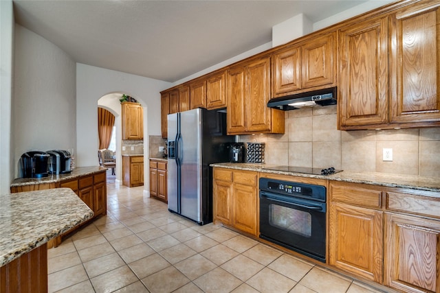 1113 Waterford Way, Allen, TX 75013 - kitchen with black appliances, under cabinet range hood, arched walkways, decorative backsplash, and brown cabinets
