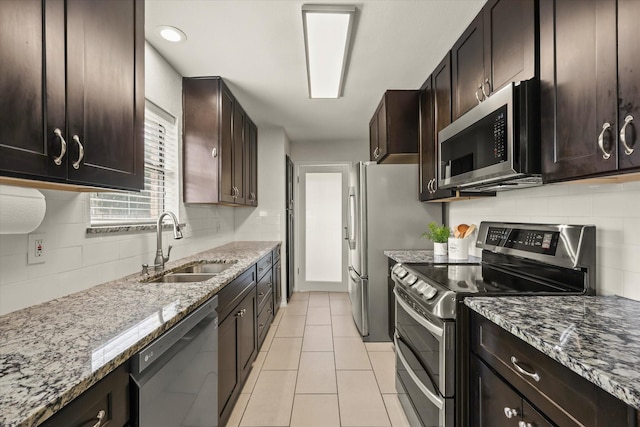 1646 Belltower Dr, Lewisville, TX 75067 - kitchen featuring stainless steel appliances, a sink, decorative backsplash, light stone countertops, and dark brown cabinets