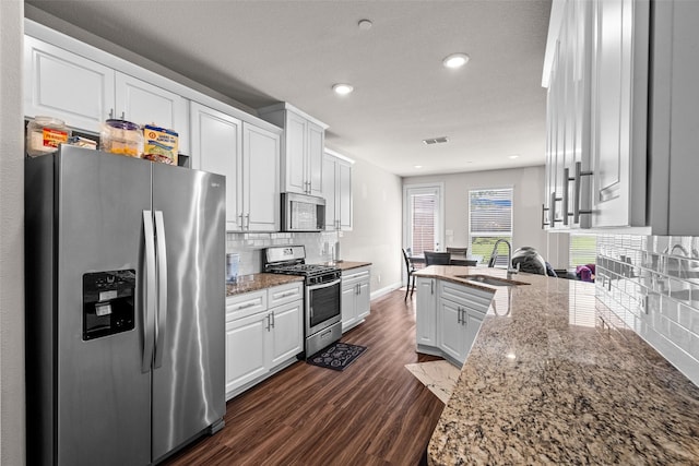 3657 Harebell Dr, Carrollton, TX 75007 - kitchen with appliances with stainless steel finishes, a sink, dark wood-style floors, a peninsula, and white cabinetry