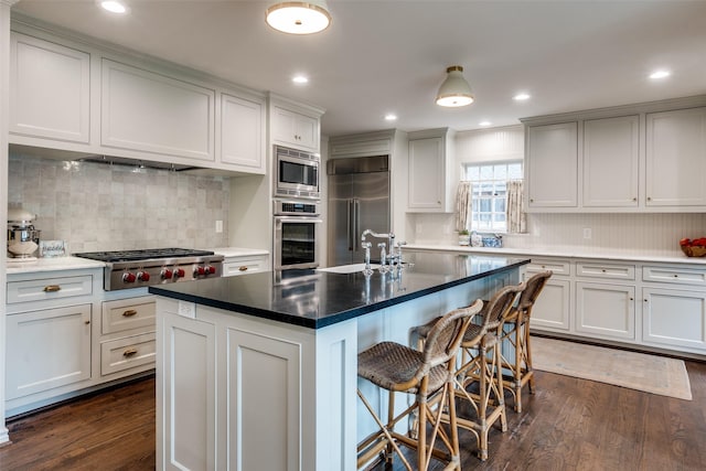 4560 Lorraine Ave, Highland Park, TX 75205 - kitchen with built in appliances, dark wood-type flooring, a sink, tasteful backsplash, and a breakfast bar area