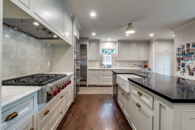 4560 Lorraine Ave, Highland Park, TX 75205 - kitchen with under cabinet range hood, appliances with stainless steel finishes, a sink, an island with sink, and dark wood-style flooring