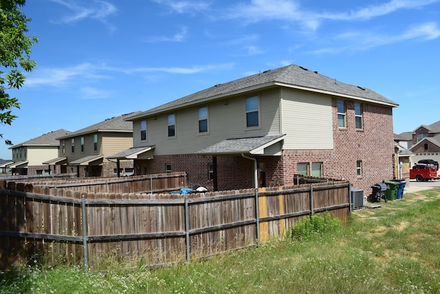 4909-4911 Villas Dr, Sanger, TX 76266 - back of property featuring brick siding, central AC unit, and a residential view