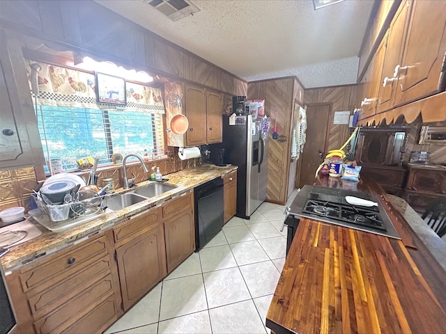 21363 Stevenson Rd, Frankston, TX 75763 - kitchen with black appliances, a textured ceiling, a sink, light tile patterned floors, and wood walls
