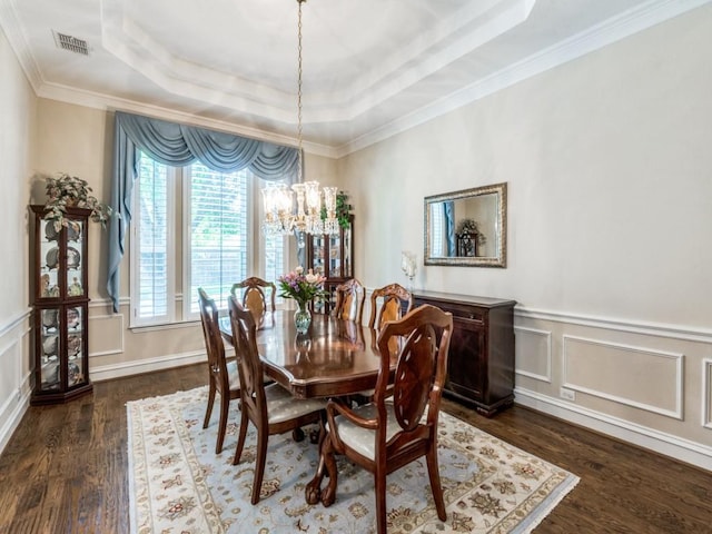 7805 Chapel View Dr, Mckinney, TX 75072 - dining area featuring a tray ceiling, dark wood-type flooring, a chandelier, a decorative wall, and crown molding
