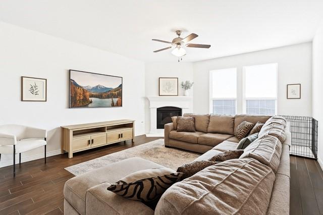 11216 Ponderosa Trl, Aubrey, TX 76227 - living area with ceiling fan, dark wood finished floors, a glass covered fireplace, and baseboards