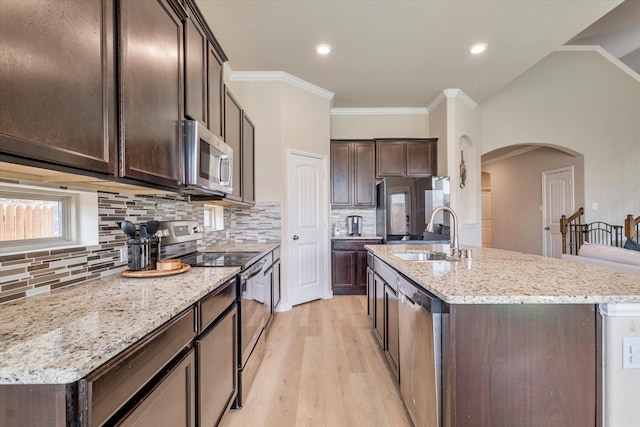 4708 River Edge Pl, Frisco, TX 75036 - kitchen with appliances with stainless steel finishes, a sink, arched walkways, dark brown cabinetry, and an island with sink