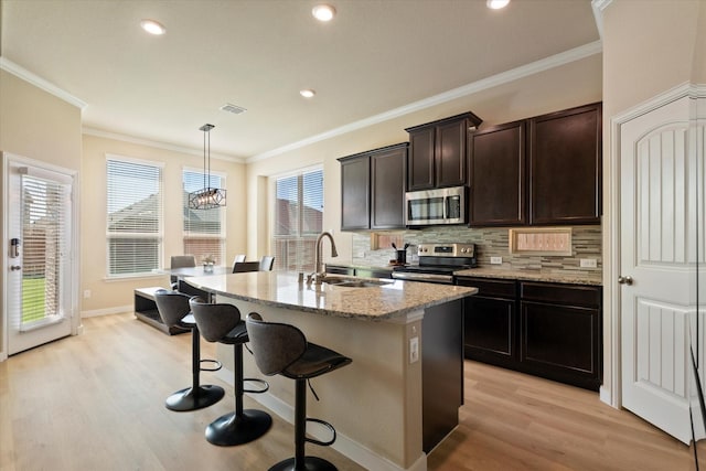 4708 River Edge Pl, Frisco, TX 75036 - kitchen featuring appliances with stainless steel finishes, a sink, light wood-style flooring, a kitchen breakfast bar, and tasteful backsplash
