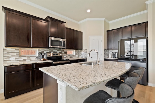 4708 River Edge Pl, Frisco, TX 75036 - kitchen with stainless steel appliances, a sink, a breakfast bar area, light wood-type flooring, and light stone counters