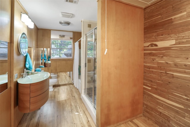 205 N College St, Mckinney, TX 75069 - bathroom with toilet, vanity, wooden walls, wood finished floors, and a stall shower