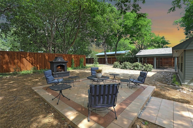 205 N College St, Mckinney, TX 75069 - patio terrace at dusk featuring a lit fireplace, a patio, and a fenced backyard