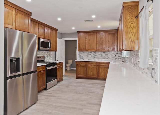 2908 Longfellow Ln, Denton, TX 76209 - kitchen with stainless steel appliances, a sink, brown cabinets, light countertops, and tasteful backsplash