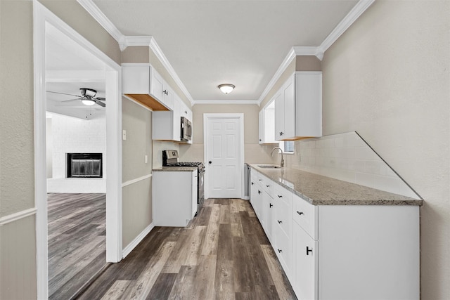 3412 Lisbon Dr, Waco, TX 76706 - kitchen with stainless steel appliances, a ceiling fan, dark wood-type flooring, a fireplace, and white cabinets