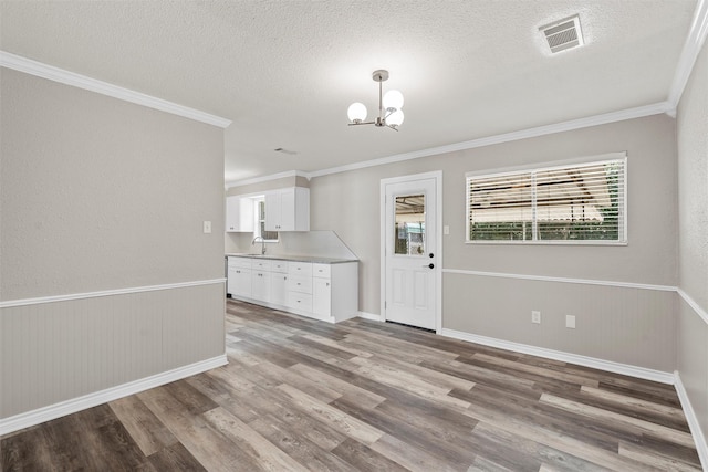 3412 Lisbon Dr, Waco, TX 76706 - unfurnished dining area with light wood finished floors, a sink, a chandelier, a textured ceiling, and crown molding