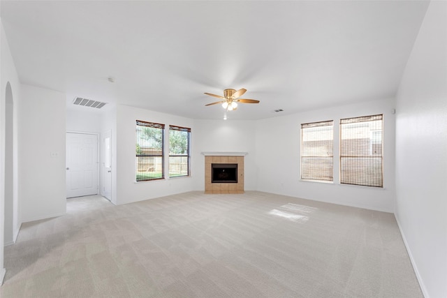 2442 Mackinac Dr, Frisco, TX 75033 - unfurnished living room featuring ceiling fan, light carpet, a tiled fireplace, and arched walkways