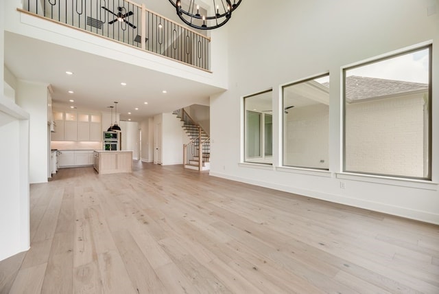 3340 Crescent Ln, Celina, TX 75009 - unfurnished living room featuring a chandelier, light wood-type flooring, stairs, a high ceiling, and recessed lighting
