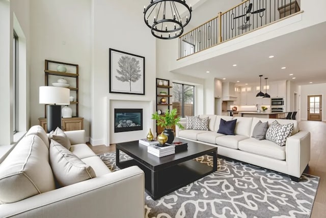 3340 Crescent Ln, Celina, TX 75009 - living area with wood finished floors, a towering ceiling, a chandelier, a glass covered fireplace, and recessed lighting