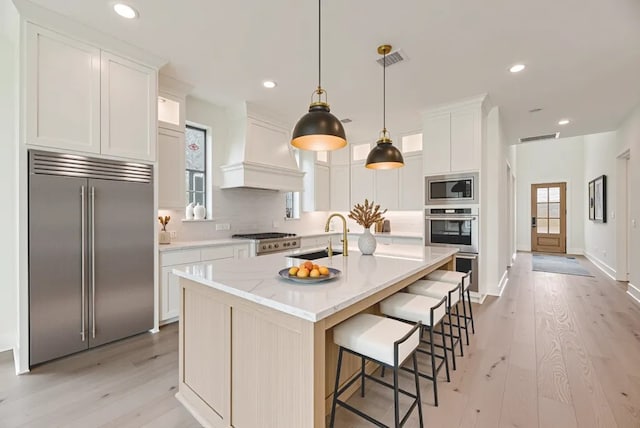 3340 Crescent Ln, Celina, TX 75009 - kitchen featuring built in appliances, custom exhaust hood, light wood-style floors, recessed lighting, and a breakfast bar