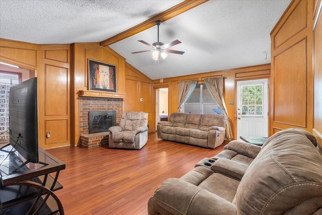 4206 Windhurst Dr, Arlington, TX 76015 - living area featuring wood finished floors, ceiling fan, a fireplace, a textured ceiling, and wood walls