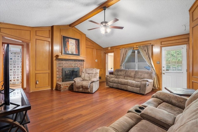 4206 Windhurst Dr, Arlington, TX 76015 - living room with a ceiling fan, wood finished floors, a fireplace, a textured ceiling, and wooden walls
