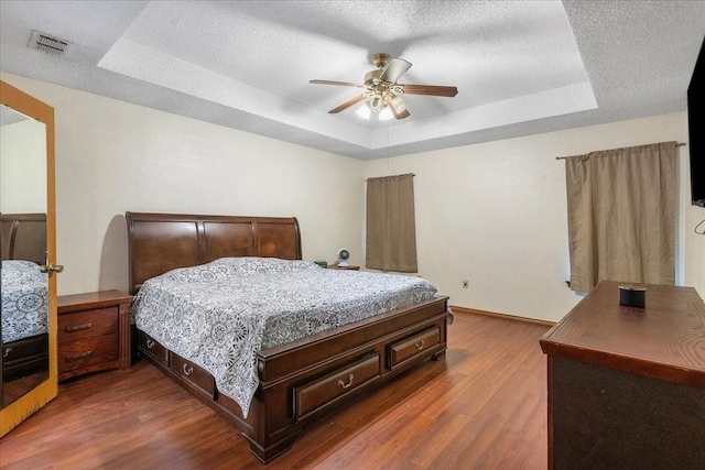 4206 Windhurst Dr, Arlington, TX 76015 - bedroom featuring a raised ceiling, dark wood-style flooring, baseboards, a ceiling fan, and a textured ceiling