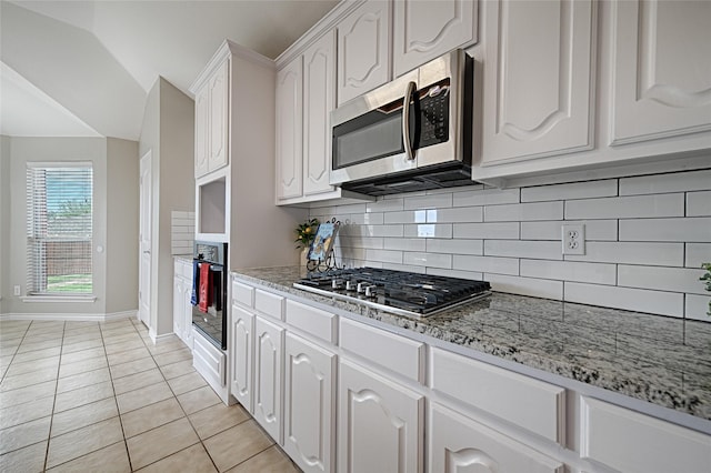 1223 Hampton Bay Dr, Rockwall, TX 75087 - kitchen with appliances with stainless steel finishes, baseboards, decorative backsplash, light tile patterned floors, and white cabinets
