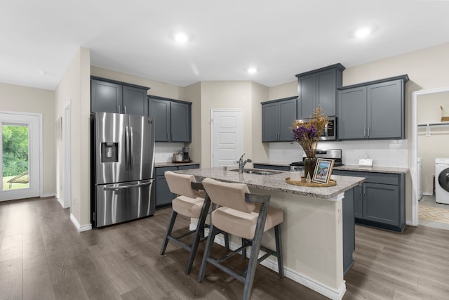 1304 Villalonga Dr, Little Elm, TX 75068 - kitchen with appliances with stainless steel finishes, a sink, washer / dryer, wood finished floors, and decorative backsplash