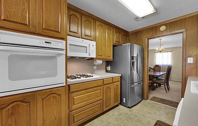 1700 Sunset Rd, Robinson, TX 76706 - kitchen with white appliances, a chandelier, brown cabinetry, light countertops, and a textured ceiling