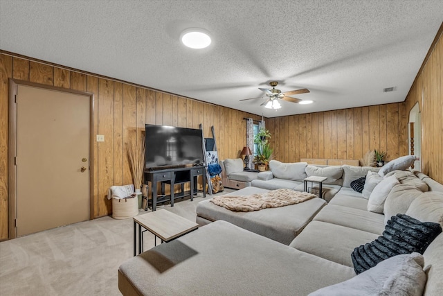 1313 Crow Dr, Waco, TX 76705 - living room featuring wood walls, a ceiling fan, light carpet, and a textured ceiling