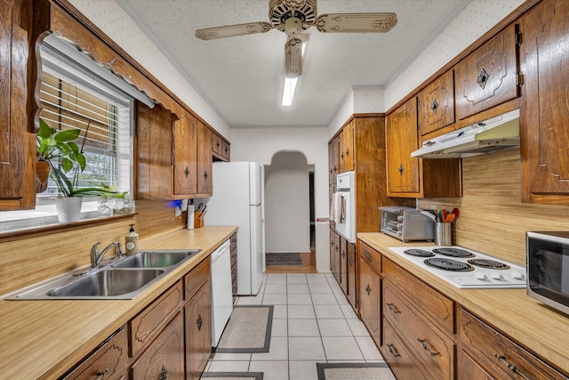 1313 Crow Dr, Waco, TX 76705 - kitchen featuring a sink, under cabinet range hood, white appliances, light countertops, and arched walkways