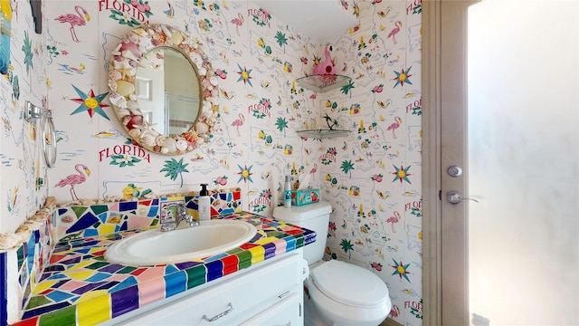 7534 Wellesley Ave, Garland, TX 75044 - bathroom with wallpapered walls, vanity, and toilet