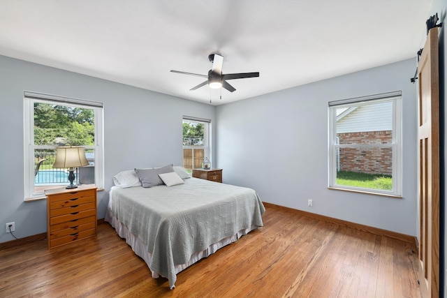 1209 Redbud Dr, Arlington, TX 76012 - bedroom with baseboards, light wood finished floors, a barn door, and a ceiling fan